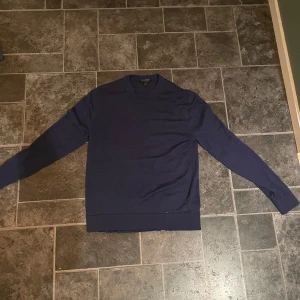 Mörkblå ulltröja från Banana Republic - Säljer en stilren mörkblå tröja från Banana Republic i 100% merinoull. Tröjan har en klassisk design med långa ärmar och rund hals. Perfekt för kyligare dagar. Typ aldrig använd 