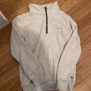 Grå Halv zip tröja från Lacoste - Snygg grå tröja från Lacoste med halv dragkedja och ribbade muddar. Tröjan är i Storlek M men passar även S skick 10/10 