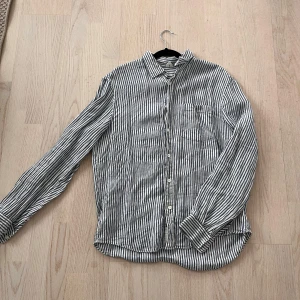 Randig skjorta i bomull - Snygg och stilren randig skjorta i blått och vitt. Skjortan har långa ärmar och knappar framtill. Perfekt för en avslappnad men ändå uppklädd look. (Ser såklart bättre ut när den är strykt)