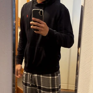 Svart hoodie med röd logga - Säljer en stilren svart hoodie med en liten röd logga på bröstet. Tröjan har en klassisk design med huva och långa ärmar. Perfekt för en avslappnad look. Nästa aldrig använt 