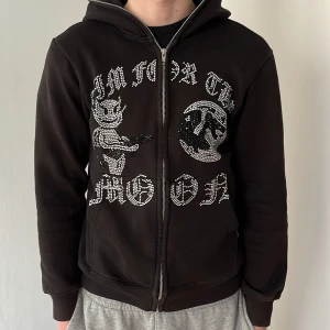 Svart huvtröja med tryck - Snygg svart huvtröja med dragkedja och med tryck framtill. Skick 8/10