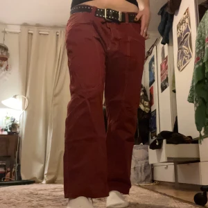 Röda baggy cargojeans - Snygga röda byxor från Fordocks i 100% bomull. De har en loose passform och är utrustade med praktiska fickor. Storleken är otydlig men skulle säga att de passar M med skärp då det är min storlek. För män kan det särkert vara annorlunda storlek.