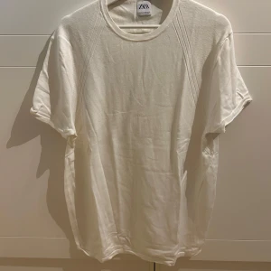 Vit t-shirt från Zara - Säljer en klassisk vit t-shirt från Zara. Den har en rund halsringning och korta ärmar, perfekt för en enkel och stilren look. Passar till många olika outfits och tillfällen.