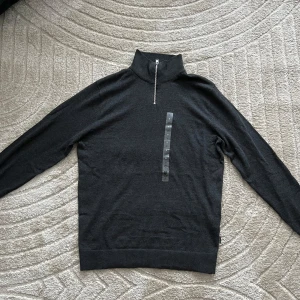 Mörkgrå polotröja med dragkedja - HELT NYTT OCH OANVÄND Snygg mörkgrå polotröja med dragkedja framtill. Perfekt för kyligare dagar med sin stilrena design och bekväma passform. 