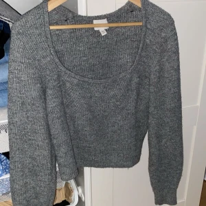 Grå stickad tröja - Mysig grå stickad tröja med rund halsringning och långa ärmar. Perfekt för kyligare dagar och enkel att matcha med olika outfits.