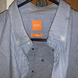 Hugo Boss skjorta - Snygg randig skjorta från Boss Orange i slim fit. Skjortan har ett diskret mönster med små broderade detaljer och knappar framtill. Perfekt för en stilren look.