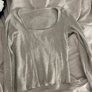 Grå ribbad långärmad topp - Säljer en stilren grå ribbad topp med långa ärmar och fyrkantig halsringning. Perfekt för lager-på-lager eller som den är. Passar till både jeans och kjol!