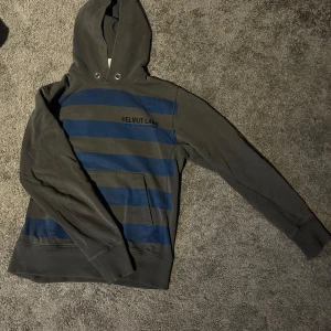 Helmut Lang Hoodie - Tja, säljer min as feta och unika Helmut Lang hoodie. Nypris ligger upp mot dryga 2000kr men säljs för endast 799kr! Storlek M och är i topp skick. Hör av dig vid frågor o funderingar!