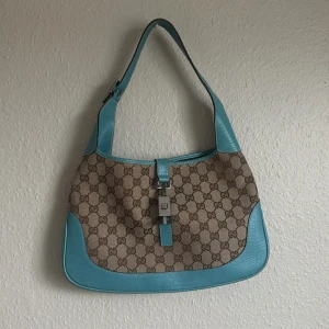 Gucci jackie turkos - Väskan är jätte ovanlig och därav super svår att få tag på. Monogrammet är i perfekt skick. Det finns små små slitage på det blå lädret, annars är väskan i väldigt bra skick för att vara vintage. Dustbag medföljer 🩵Självklart är den äkta! 