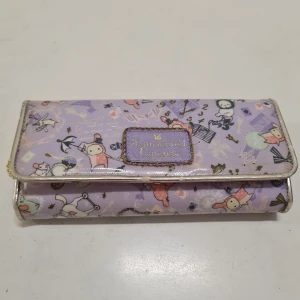 Sentimental Circus plånbok ljuslila - Superfin ljuslila plånbok med Sentimental Circus tema. Den har flera fack inuti för kort och sedlar, samt en dragkedja för bättre säkerhet. Perfekt för att hålla ordning på dina grejer med stil! 💜 Använt skick. Kom gärna med prisförslag!