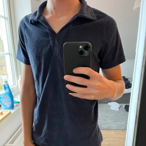 Mörkblå pikétröja från SOC - Säljer en snygg marinblå pikétröja från SOC i storlek S. Perfekt för både vardag och lite mer uppklädda tillfällen. Tröjan har en klassisk krage och korta ärmar, vilket gör den superbekväm och stilren. Passar perfekt till allt!! Materialet är frotté 