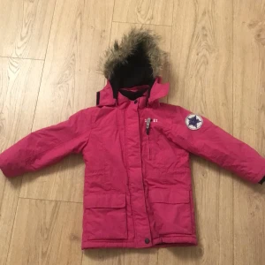 Snygg jacka - Snygg rosa jacka, med numret 12 i en stjärna på axeln. Jackan har lite päls på luvan!