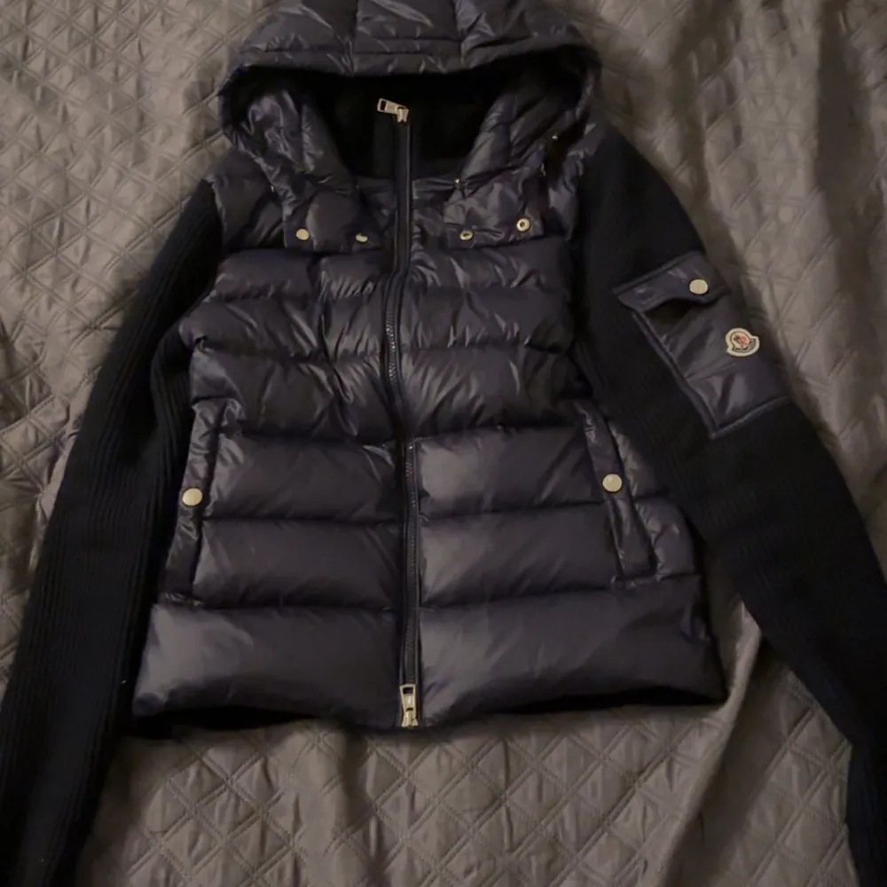 Säljer en snygg mörkblå cardigan från Moncler. Jackan har en quiltad design med dragkedja och huva. Den är långärmad med ribbade ärmar och har en cool ficka med knappdetalj på ärmen. Perfekt för höst och vinter! jackan är såklart äkta och om ni har fler frågor så skriv till mig, priset kan diskuteras.. Jackor.