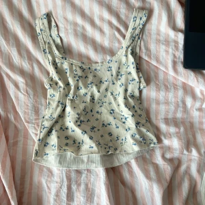 Blommig linnetopp - Söt blommig linnetopp i beige med små blå blommor. Passar bra till både jeans och kjol.