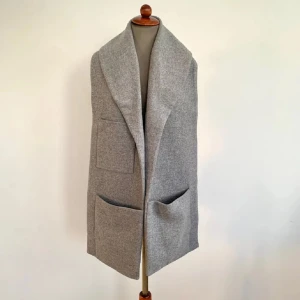 Grå ullväst med stora fickor - Säljer en stilren grå väst i ull med stora fickor fram. Perfekt för lager-på-lager under höst och vinter. Västen har en öppen design utan knappar och dragkedja. Nypris: 890kr. Säljer för endast 550kr