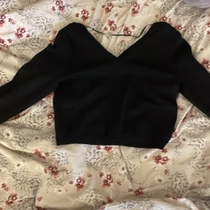 Svart långärmad topp med v-ringning - Säljer en stilren svart topp med v-ringning och långa ärmar. Den har ett subtilt sicksackmönster som ger en extra touch. Perfekt för både vardag och fest! 🖤