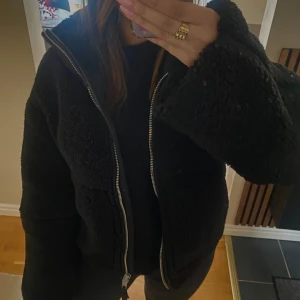 Teddyjacka  - Svart teddyjacka från H&M med silverdragkedja. Denna jacka är mycket populär och helt slutsåld i butikerna. Jackan är i utmärkt skick och har knappt använts. Tryck ej ”köp direkt”.
