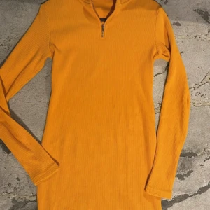 Orange ribbad tröja med dragkedja - Säljer en snygg orange ribbad tröja med dragkedja i halsen. Perfekt för höst och vår med sin långa ärmar och sköna passform. Tröjan är i nyskick och passar både till vardags och lite mer avslappnade tillfällen. 🧡