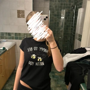 Svart t-shirt med bi-tryck från New Yorker - Säljer en svart t-shirt från New Yorker i storlek XS. Den har ett gulligt tryck med texten 'Happy to bee with you' och två små bin. Perfekt för en avslappnad dag eller sommarhäng! 🐝