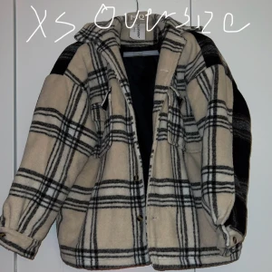 Rutig overshirt jacka - Säljer en supercool rutig overshirt i beige och svart. Den är oversized och perfekt för lager på lager-stilen. Jackan har långa ärmar och knappar framtill. Perfekt för höst och vår!