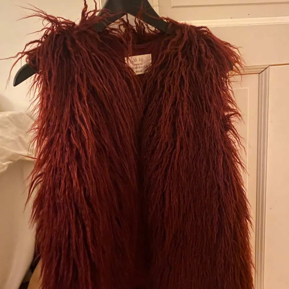 Säljer en supercool vinröd pälsväst som är perfekt för höst och vinter. Västen är i ett fluffigt material som ger en lyxig känsla. Den är i normal passform och kan enkelt stylas över en t-shirt eller tröja för en trendig look. Passar S och M. Takit.