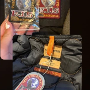 Svart jacka från Parajumpers - Säljer en svart jacka från Parajumpers i storlek L. Jackan är perfekt för vintern med sitt varma och slitstarka material. Den har en luva och flera praktiska fickor med dragkedjor och knappar. Detaljer som en gul rem och märkeslogga på ärmen gör den extra snygg. Jackan är i nyskick och redo för nya äventyr!