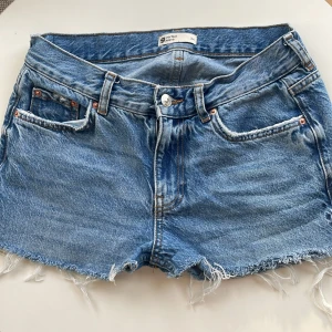 Blå jeansshorts från Gina  - Säljer ett par snygga blå jeansshorts från Gina tricot i storlek 34. De är Low Waits med slitna kanter och i väldigt bra skick.💗