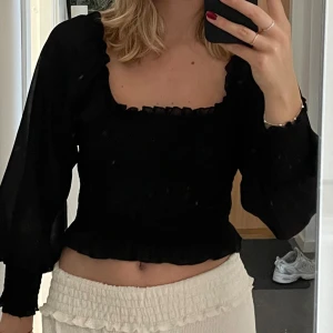 Svart topp puffärm - En svart topp i meshtyg med puffiga ärmar. Kan användas på flera sätt. 