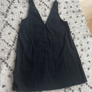 Svart ärmlös klänning - Säljer en snygg svart ärmlös klänning. Den är kort och har en djup v-ringning. Perfekt för fest eller en utekväll. Klänningen är i nyskick och passar bra till både sommar och vår. storlek S