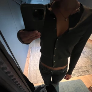 Mörkgrön kofta med knappar - Säljer en snygg mörkgrön kofta i storlek xs. Den har långa ärmar och knappar hela vägen ner. Perfekt för höst och vinter, och kan lätt matchas med jeans eller kjol. Koftan är i bra skick och supermjuk!