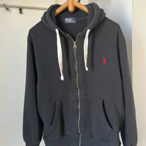 Ralph Lauren Full Zip Hoodie - En svart full zip hoodie från Ralph lauren i näst intill perfekt skick utan några som helst defekter👍  Perfekt nu inför hösten 🍁 Den passar mig som på bilden och jag är 176 cm och väger runt 70 kg