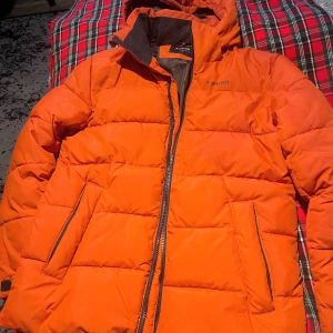 Orange pufferjacka från Everest - Säljer en snygg och varm orange pufferjacka från Everest som är använt ett par gånger! .Jackan har en dragkedja framtill och två fickor med dragkedjor. Den är perfekt för kalla vinterdagar och håller dig varm och bekväm. Jackan är i bra skick och redo för en ny ägare! Finns ingen skada på jackan! 
