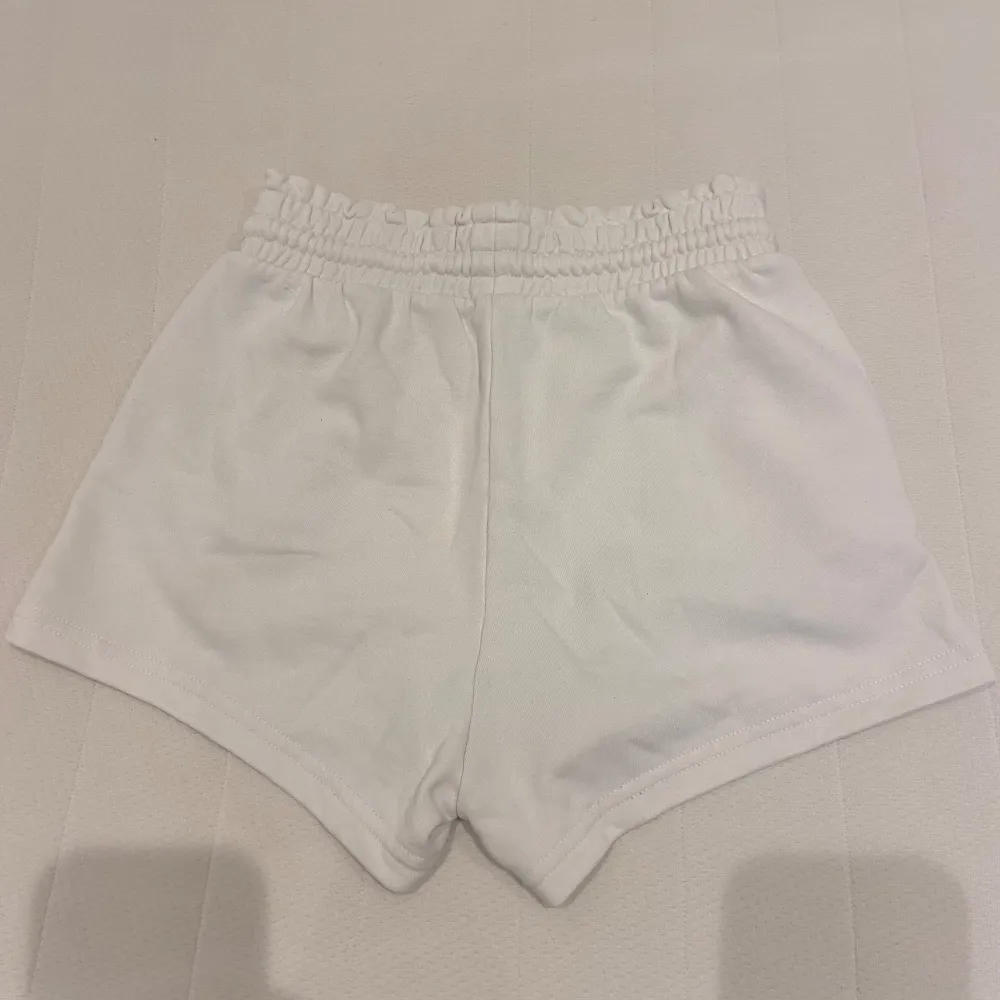 Säljer ett par vita shorts med dragsko i midjan. De är superbekväma och perfekta för sommaren. Shortsen har en elastisk midja och är gjorda av mjukt material. Perfekta för en avslappnad dag eller träning!. Shorts.