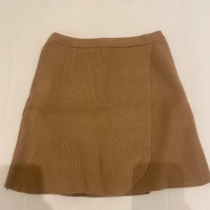 Beige stickad kjol - Säljer en superfin beige stickad kjol. Den är kort och har en enkel men stilren design. Perfekt för höst och vinter, och kan stylas både upp och ner beroende på tillfälle. Kjolen är i nyskick och har en normal passform. Den är gjord av ett mjukt och bekvämt material som håller dig varm under kallare dagar.