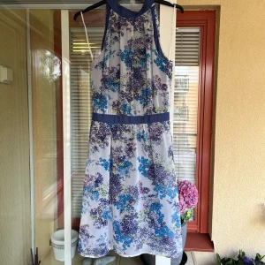 Blommig klänning från Esprit - Säljer en superfin blommig klänning från Esprit. Den är vit med ett färgglatt blommönster i blått, lila och grönt. Klänningen är ärmlös och har en normal passform. Endast använd ett par gånger. Perfekt för fester! 🌸