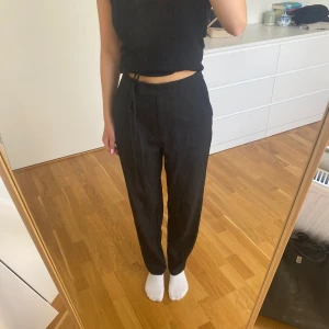 Svarta kostymbyxor  - Högmidjade svarta kostymbyxor med knytdetalj framtill. Fina men kommer tyvärr inte till användning.