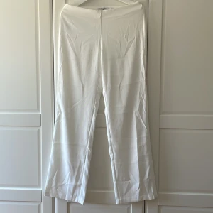 Vita lågmidjade kostymbyxor från NaKD  - Vita lågmidjade kostymbyxor från NaKD i strl 34 men lite stora i storlek så passar 36. Raka i modellen och lite lösa i modellen, fint fall