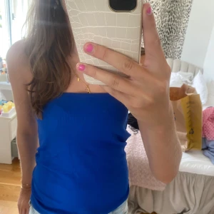 Blå tubtopp - Säljer en snygg blå tubtopp i storlek S. Perfekt för sommaren och festliga tillfällen. Toppen är ärmlös och har en tight passform som framhäver figuren. Materialet känns mjukt och bekvämt mot huden.