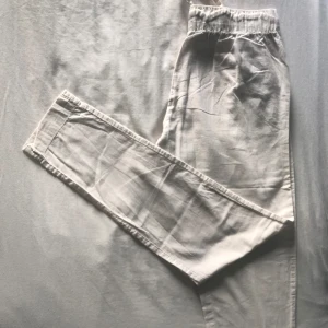 Beige mjukisbyxor med snörning - Säljer ett par bekväma vita linnebyxor med elastisk midja och snörning. Byxorna har en avslappnad passform och är perfekta för en chill dag hemma eller en avslappnad promenad. De är tillverkade i ett mjukt och skönt material som känns bra mot huden. Byxorna har också praktiska fickor på sidorna.