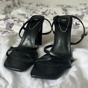 Svarta klackskor från Zara - Säljer ett par snygga svarta klackskor från Zara i storlek 40. De har en elegant design med smala remmar och en fyrkantig tå. Perfekta för fest eller en utekväll! Använda Max 3 ggr så skicket är jättefint