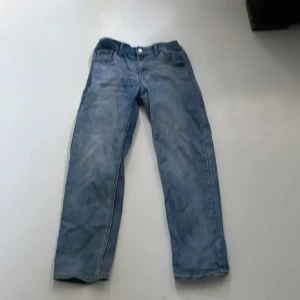 Blå jeans från Levis - Säljer ett par klassiska blå jeans från Levis. De är i bra skick och har en snygg, lite sliten look. Perfekta för vardagsbruk och kan matchas med nästan vad som helst. De har en knapp och dragkedja framtill samt fem fickor.