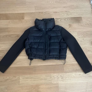 Svart croppad pufferjacka från Zara - Säljer en supercool svart croppad pufferjacka från Zara. Den har en hög krage och dragkedja framtill. Bra för höst och vinter. Jackan är i nyskick och har en tight passform som ger en snygg form