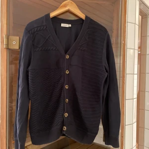 Svart kofta från J.Lindeberg - Säljer en stilren svart mönstrad kofta från J.Lindeberg i storlek M. 