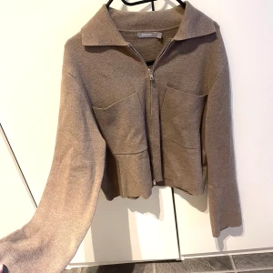 Beige jacka från Åhléns - Säljer en snygg beige kofta från Åhléns. Den har en dragkedja framtill och två stora fickor. Storlek S