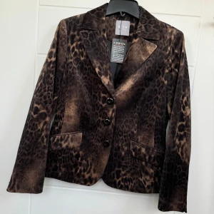 Elegans Kavaj, Helt Ny. - Kavaj från KSTN Helt ny med prislapp kvar. Längd: 58 cm Bredd: 49 cm Ordinarie pris: 1498 kr, men nu endast 149 kr! Ett fantastiskt fynd för den som vill ha något unikt och stilrent. Kontakta mig vid intresse! 