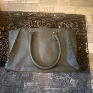 Svart axelväska med dragkedja - Säljer en stilren svart axelväska i skinn. Väskan har en praktisk dragkedja upptill och en extra ficka med dragkedja på framsidan. Perfekt för både vardag!