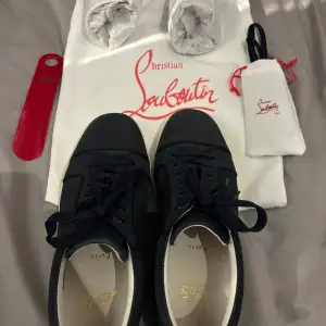 Säljer ett par snygga svarta sneakers från Christian Louboutin som jag fick för ett tag sen. Skorna är använda men i bra skick. Skorna har den ikoniska röda sulan och är i storlek 42. Perfekta för både vardag och fest! Kommer med originalpåse och skohorn. Tyvärr är skokartongen borta. Ny pris ca 7000