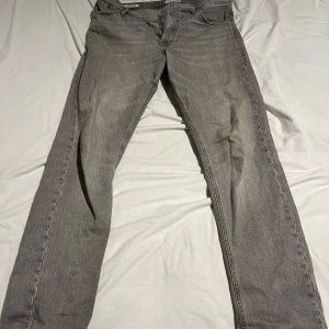 Gråa Loose chris jeans - Säljer dessa snygga jack&jones jeans på grund av att dom blivit för små. Dom är slitna mellan bena men det är lagat och det är inget som syns. Storlek 31/34
