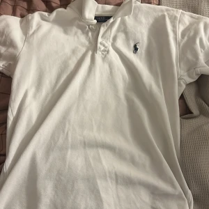 Vit pikétröja från Ralph Lauren - Säljer en klassisk vit pikétröja från Ralph Lauren i storlek S den kan passa xs med. Tröjan har en broderad logga på bröstet och knappar vid kragen. Perfekt för en stilren och avslappnad look. Passar både till vardags och festliga tillfällen. 🕶️