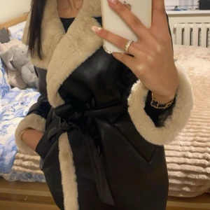 Varm fodrad vinterjacka - Säljer en otroligt snygg& varm vinter jacka . Jackan har ett bälte i midjan för en tight passform och långa ärmar med päls vid ärmsluten den är fodrad med beige päls.  Perfekt för höst och vinter!